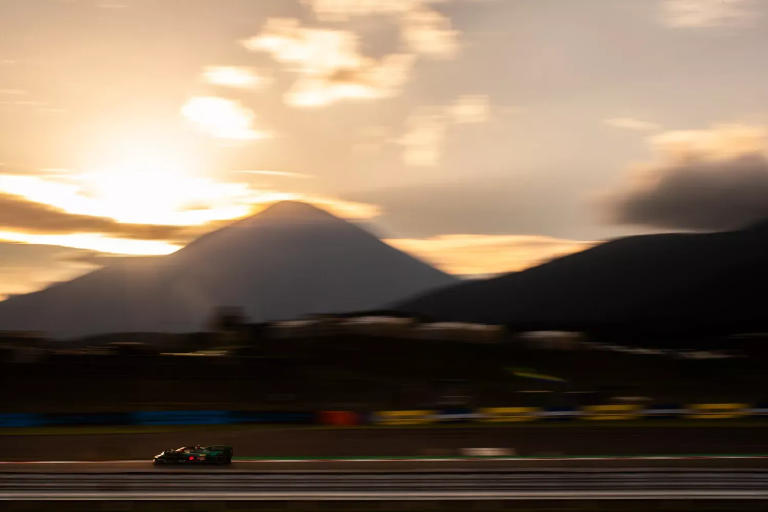 Aston Martin sports car with a long hood on a winding road in evening light