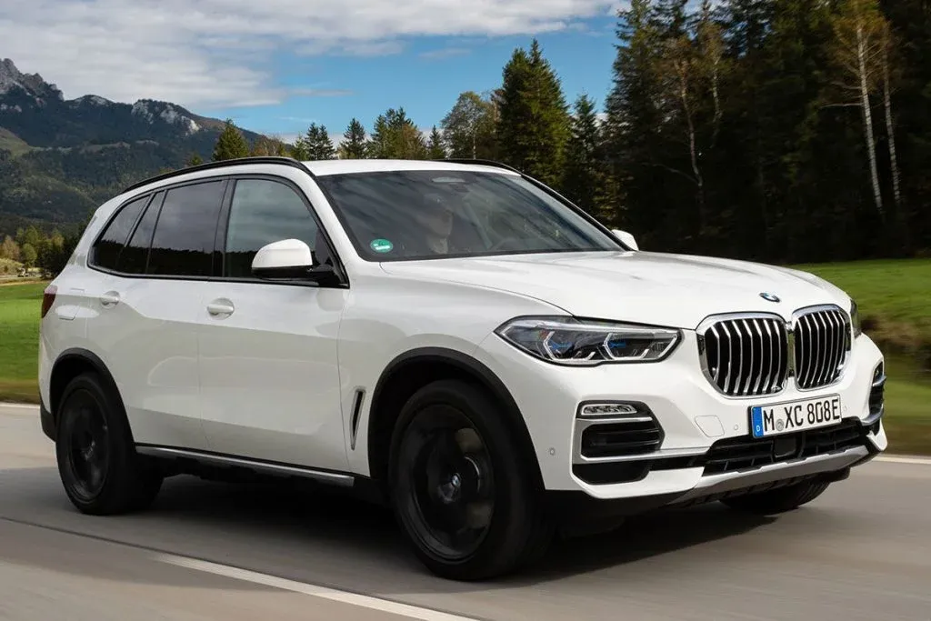 2027 BMW X5 auf einer befestigten Bergstraße mit leichtem Schotter am Straßenrand