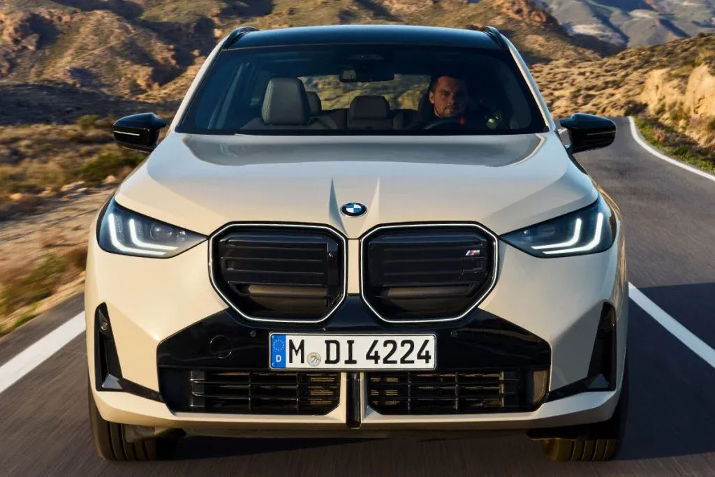 BMW X3 M50 with Black Package in dark paint, large 22-inch wheels and black accents on a winding road