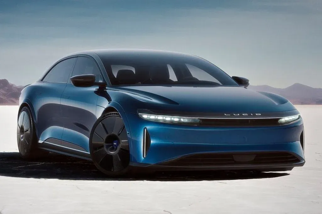 Silver Lucid Air electric sedan on a road, photographed from a front three-quarter angle in 16:9 format