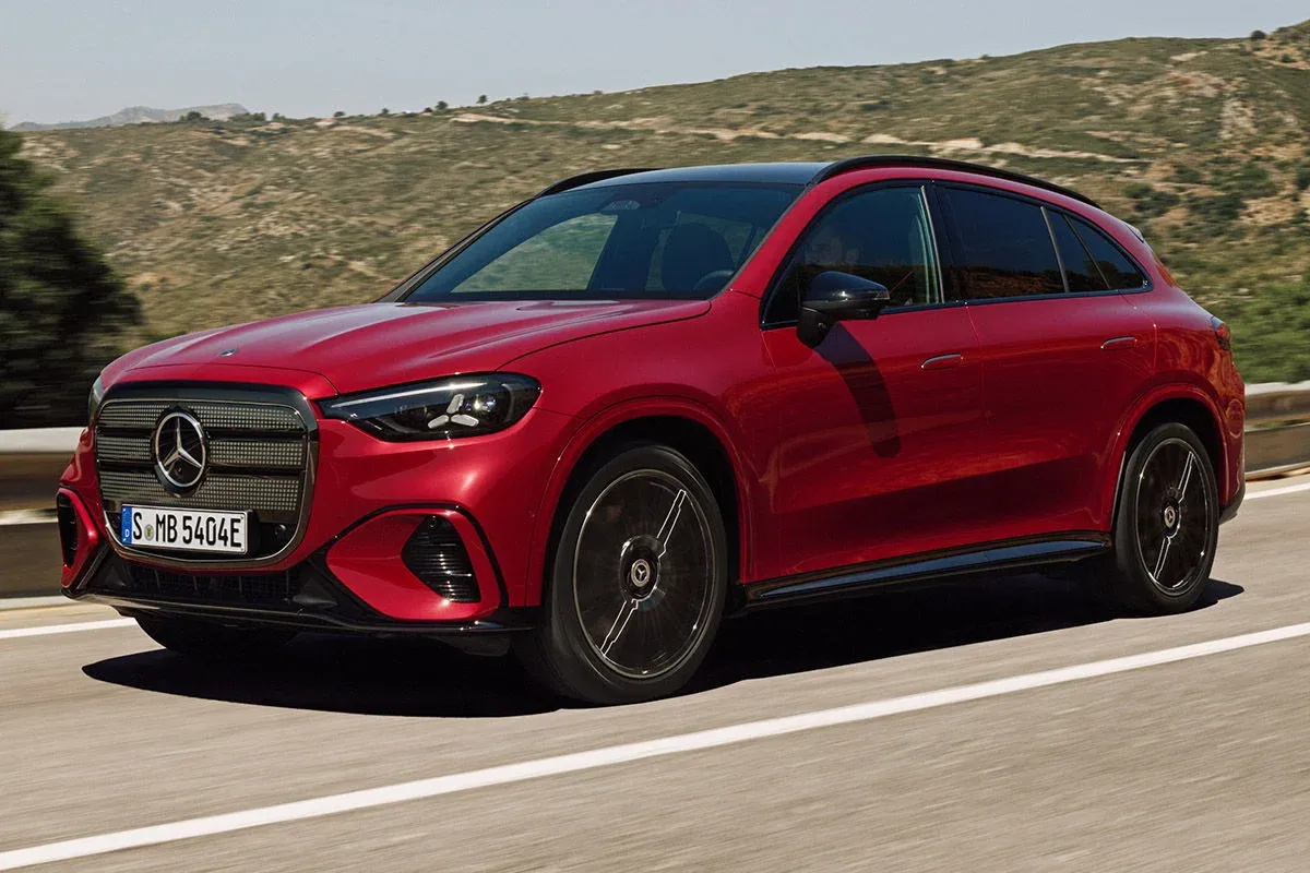 Mercedes-Benz GLC EV as a camouflaged or near-production electric SUV on a road in front of modern architecture